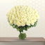 Bouquet of white roses on a wooden surface with a geometric patterned wall in the background