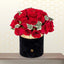 PANAMA luxury floral arrangement featuring vibrant red roses and green fillers in a black round hatbox with a gold logo.
