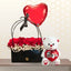 Black handbag-style flower box with red roses and baby's breath, next to a white teddy bear and a red heart balloon.