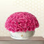 Bouquet of pink roses in a silver container against a hexagonal patterned wall.