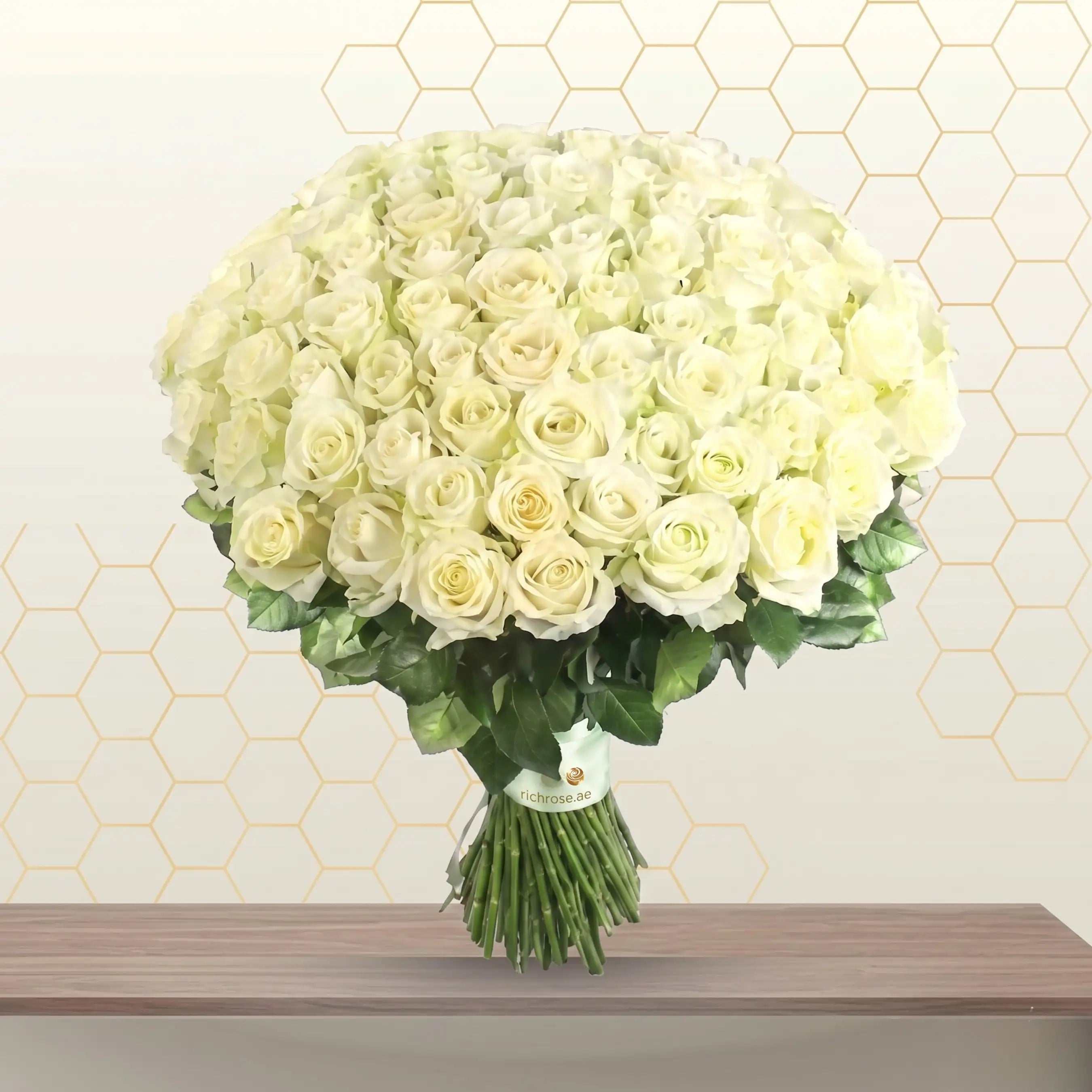 Bouquet of white roses on a wooden surface with a geometric patterned wall in the background Main image