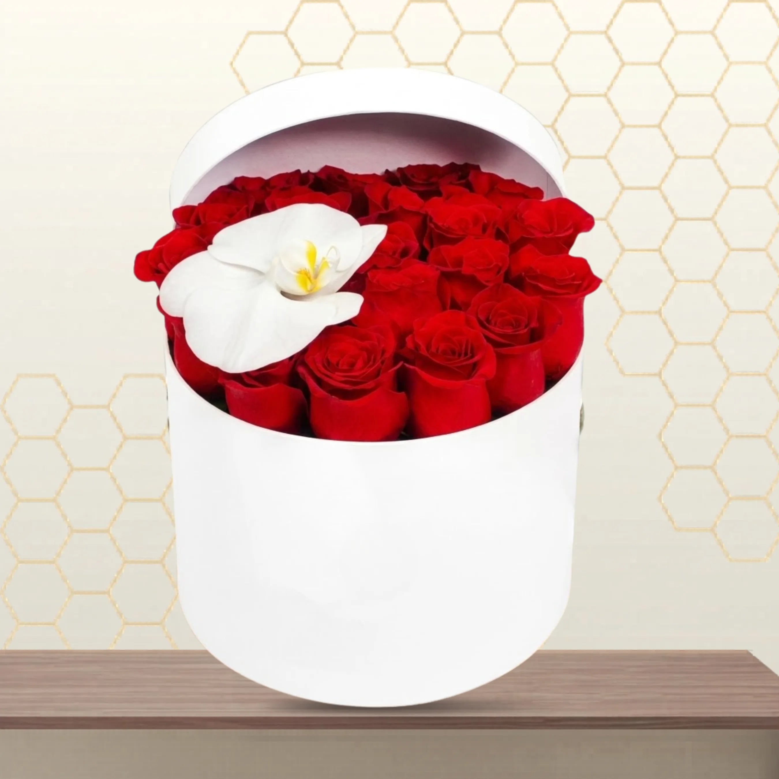 Cardiff premium flower box featuring 20 red roses and a single white orchid in a white cylindrical hatbox on a wooden table. Main image