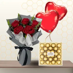 Red rose bouquet in grey wrapping with black ribbon, next to a 24-piece box of Ferrero Rocher and two heart balloons. Main image