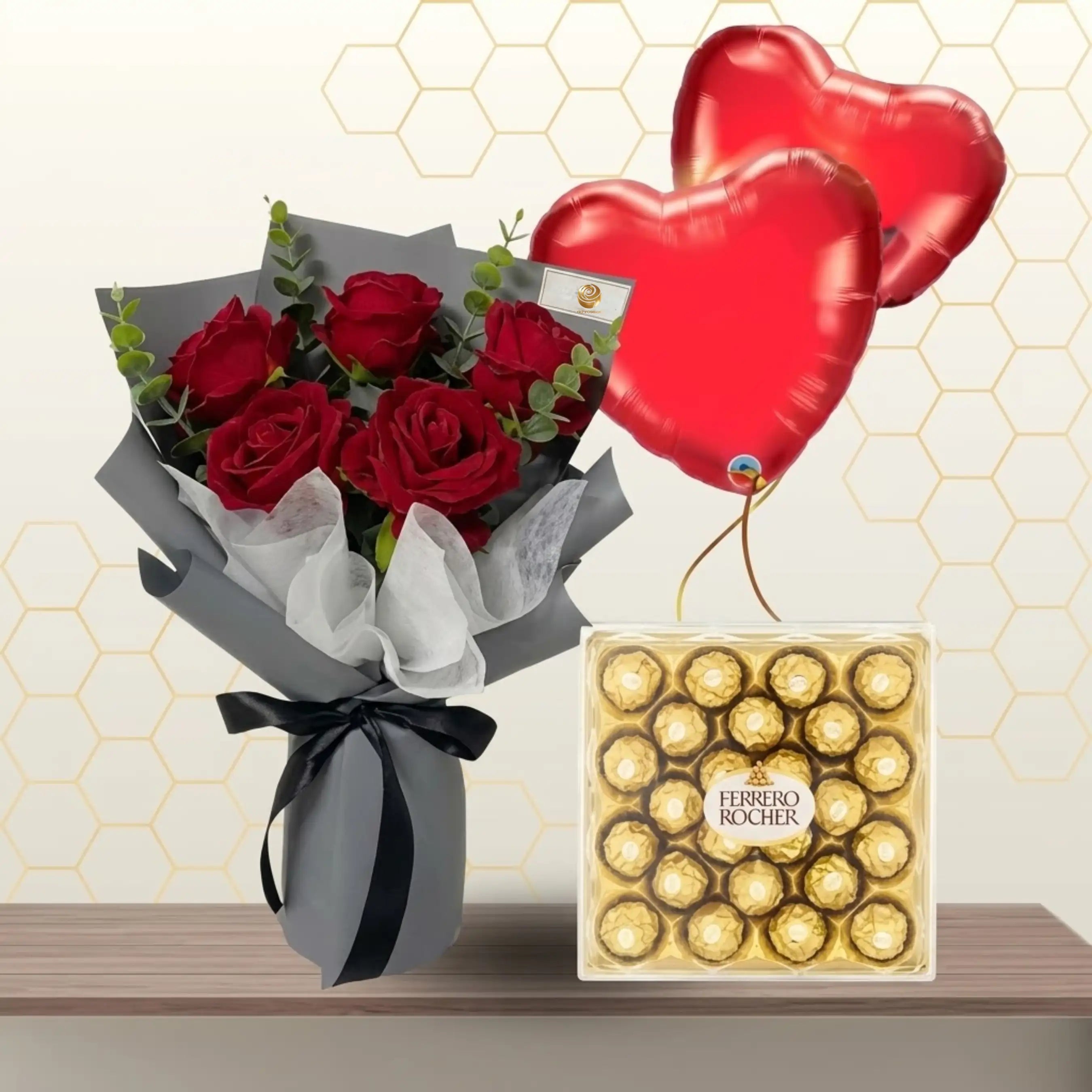 Red rose bouquet in grey wrapping with black ribbon, next to a 24-piece box of Ferrero Rocher and two heart balloons.