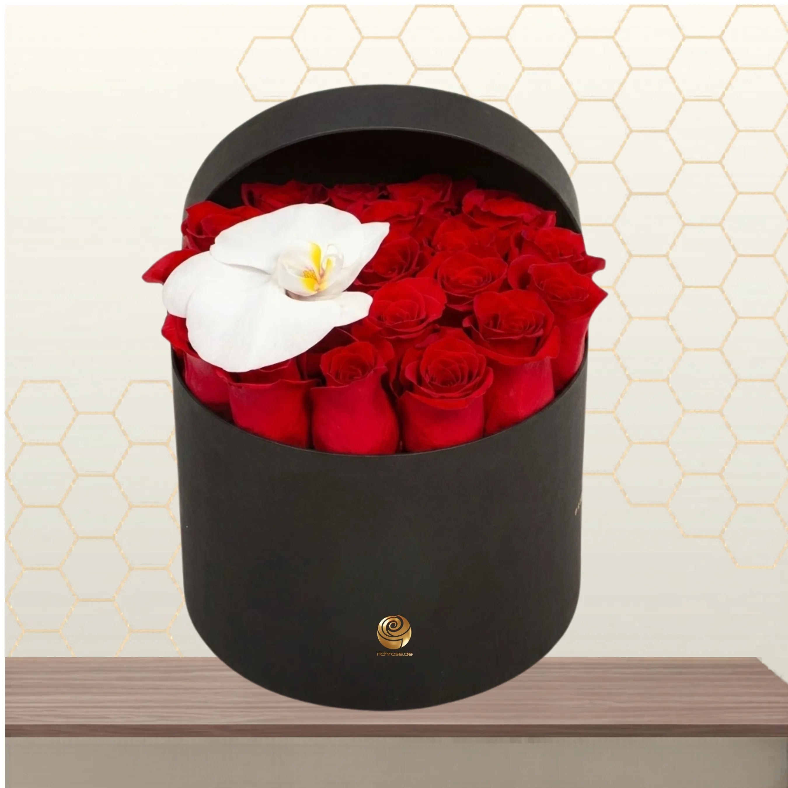 Damascus premium flower box featuring a heart-like arrangement of red roses and a single white orchid in a matte black hatbox on a wooden table. Main image