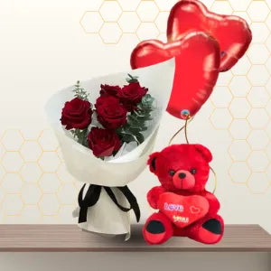 Bouquet of red roses in white paper next to a 45cm red teddy bear and two red heart balloons. Main image