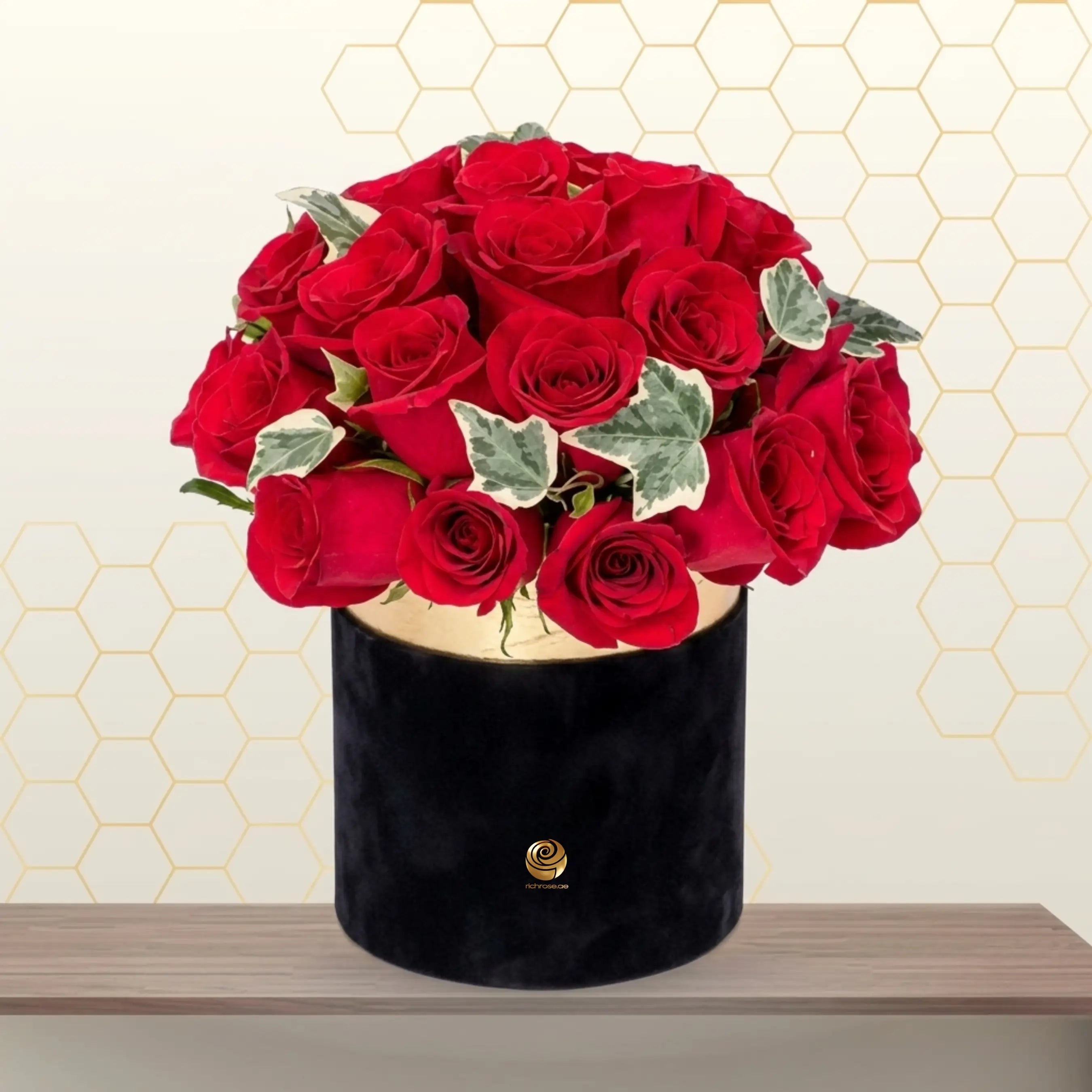 PANAMA luxury floral arrangement featuring vibrant red roses and green fillers in a black round hatbox with a gold logo. Main image