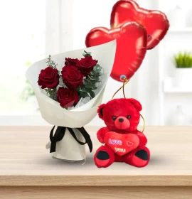 Bouquet of red roses in white paper next to a 45cm red teddy bear and two red heart balloons.